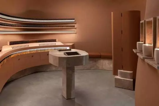 Aesop store interior with terracotta tones, curved shelves, and a central pedestal