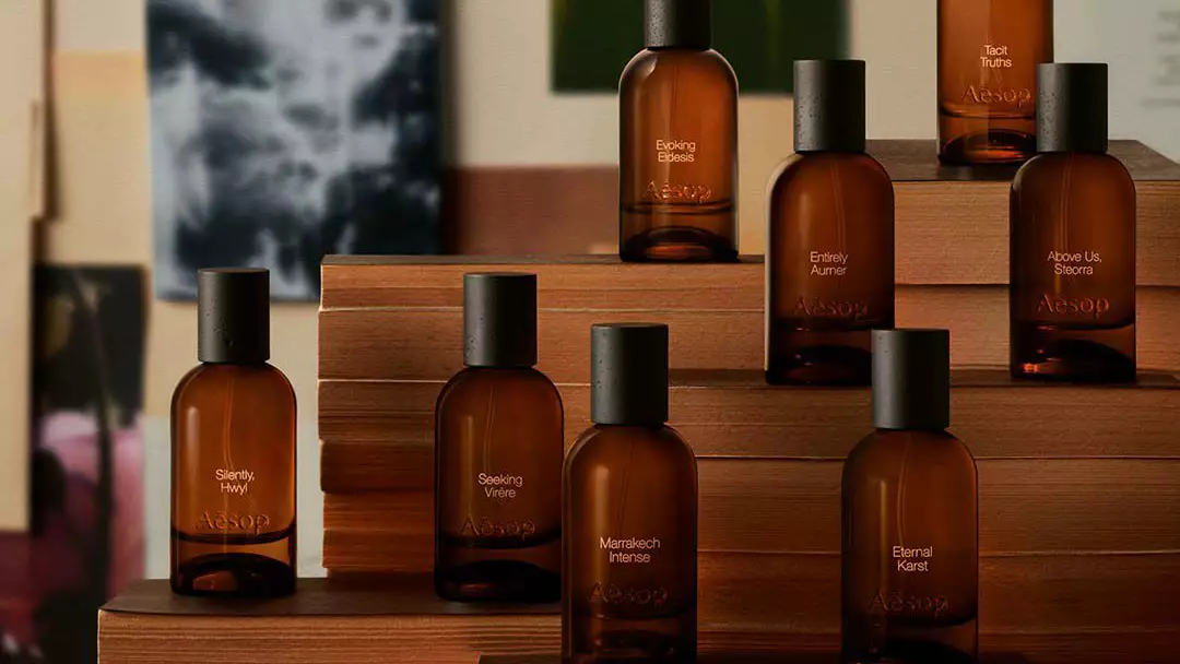 Aesop fragrance bottles arranged on tiered wooden display platforms against an editorial imagery backdrop of prints and paintings.
