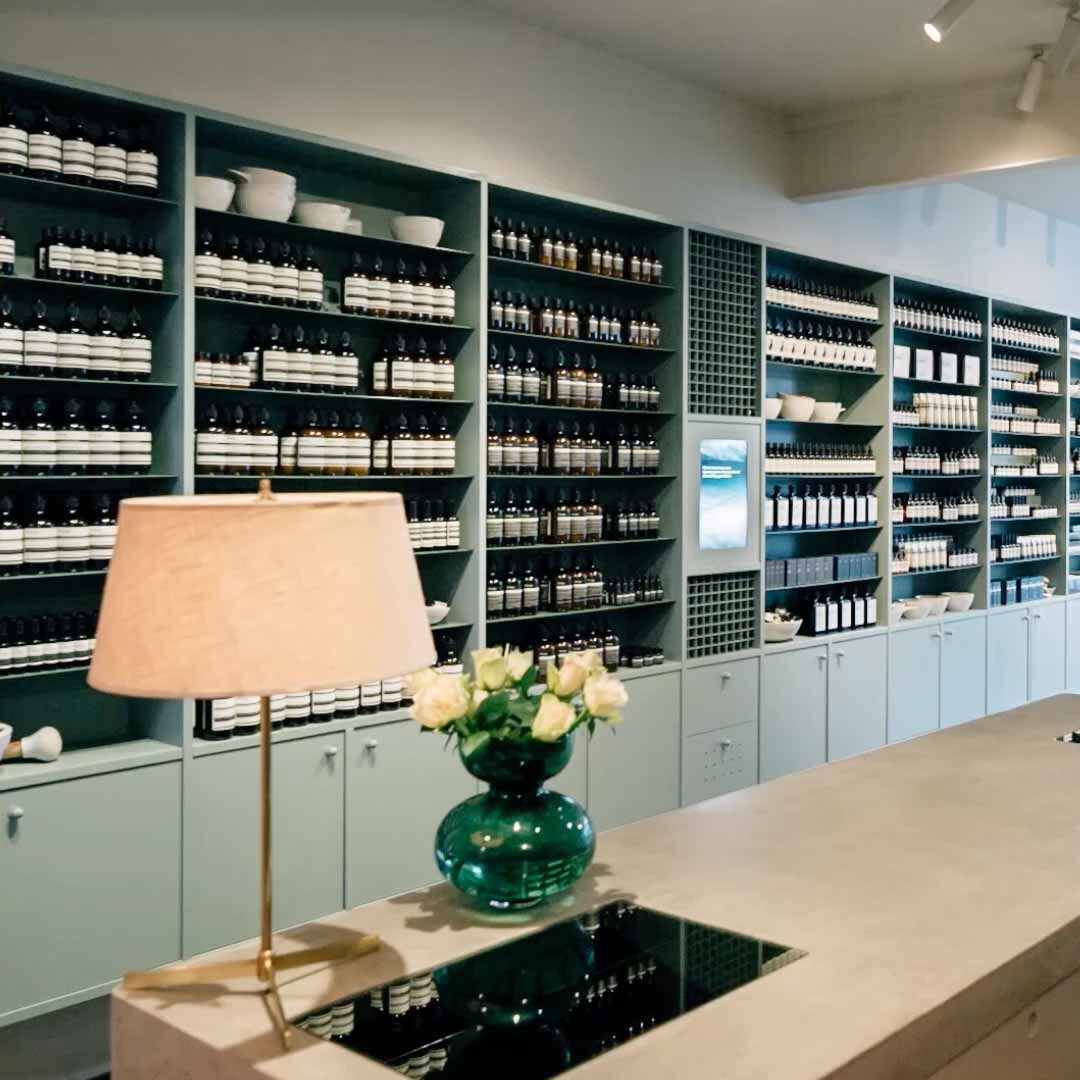 Amber bottles on shelves and flowers in an Aesop store.
