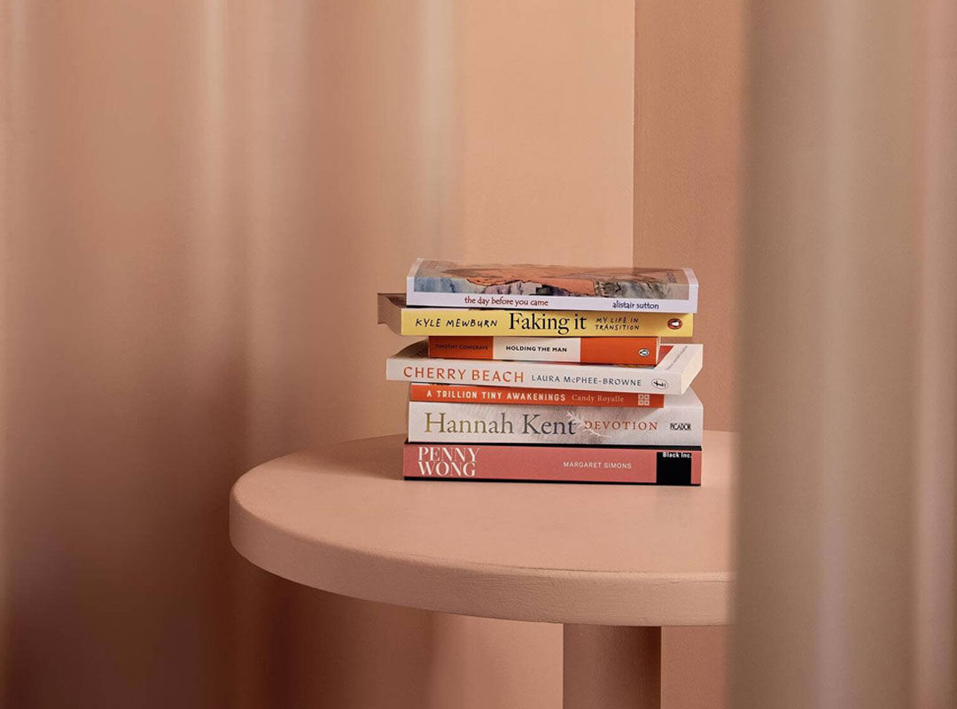 Small stack of books on a peach table against a softly draped peach backdrop.