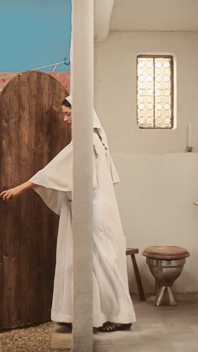 Personne en robe blanche entrant dans une salle de bain de style rustique avec une porte en bois et des toilettes