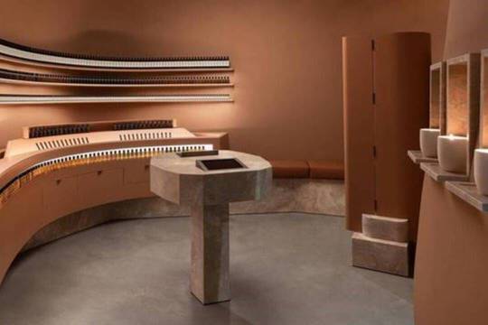 Interieur de magasin Aesop aux tons terracotta, etageres courbes et piedestal central
