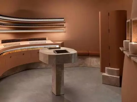 Aesop store interior with terracotta tones, curved shelves, and a central pedestal