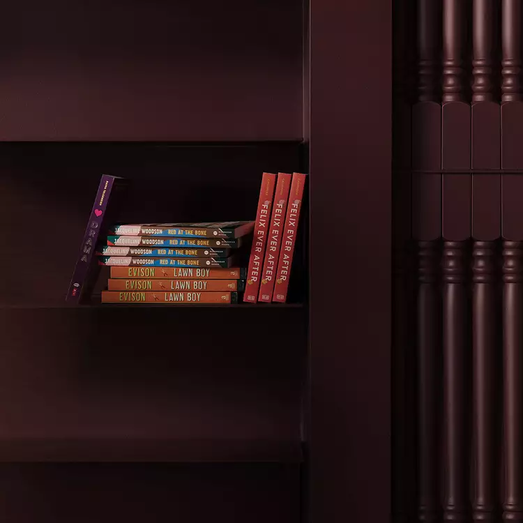 Small row of colourful books on a dark maroon shelf beside ribbed columns.