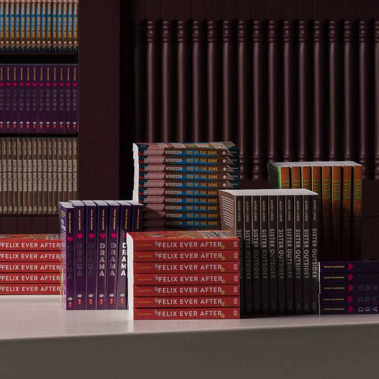 Stacks and rows of colourful books displayed on a pale table before dark ribbed shelves.