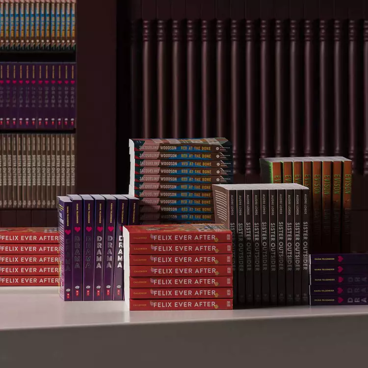 Stacks and rows of colourful books displayed on a pale table before dark ribbed shelves.