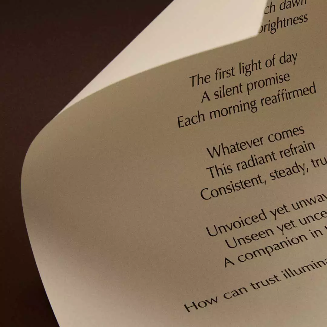Curved cream page with printed verse lit against a dark brown background.