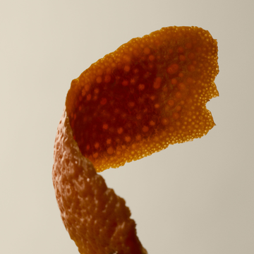 Gros plan d'une ecorce de tangerine enroulee sur fond pale.