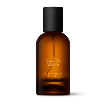 Amber glass Aesop Above Us, Steorra Eau de Parfum bottle with black cap on a white background.