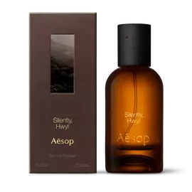 Amber glass Aesop Silently Hwyl Eau de Parfum bottle beside its brown outer box on a white background.