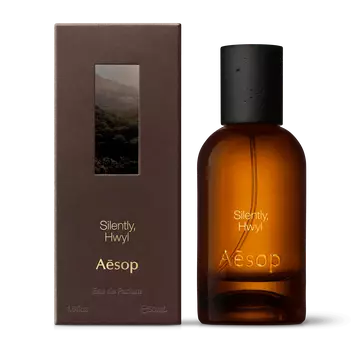 Amber glass Aesop Silently Hwyl Eau de Parfum bottle beside its brown outer box on a white background.