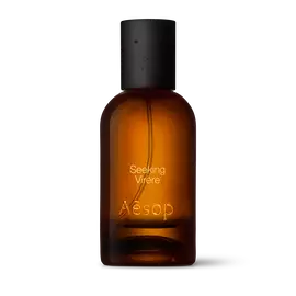 Amber glass Aesop Seeking Virere Eau de Parfum bottle with black cap on a white background.