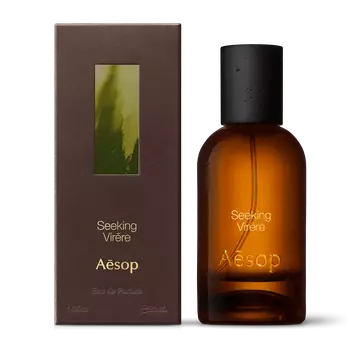 Amber glass Aesop Seeking Virere Eau de Parfum bottle beside its brown outer box on a white background.