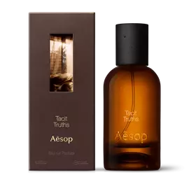 Amber glass Aesop Tacit Truths Eau de Parfum bottle beside its brown outer box on a white background.