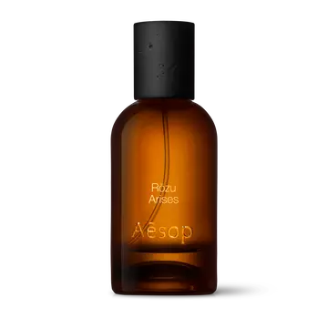 Amber glass Aesop Rozu Arises Eau de Parfum bottle with black cap on a white background.