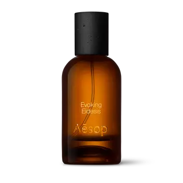 Amber glass Aesop Evoking Eidesis Eau de Parfum bottle with black cap on a white background.