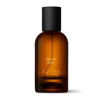 Amber glass Aesop Silently Hwyl Eau de Parfum bottle with black cap on a white background.
