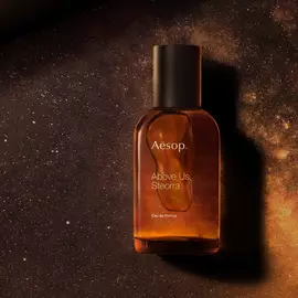 Aesop Above Us, Steorra bottle against a glowing amber speckled backdrop.