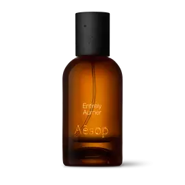 Amber glass Aesop Entirely Aurner Eau de Parfum bottle with black cap on a white background.