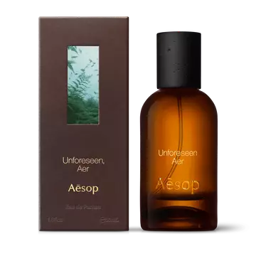 Amber glass Aesop Unforeseen Aer Eau de Parfum bottle beside its brown outer box on a white background.