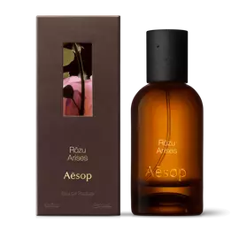 Amber glass Aesop Rozu Arises Eau de Parfum bottle beside its brown outer box on a white background.